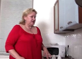 Granny stands naked in the kitchen and enjoys